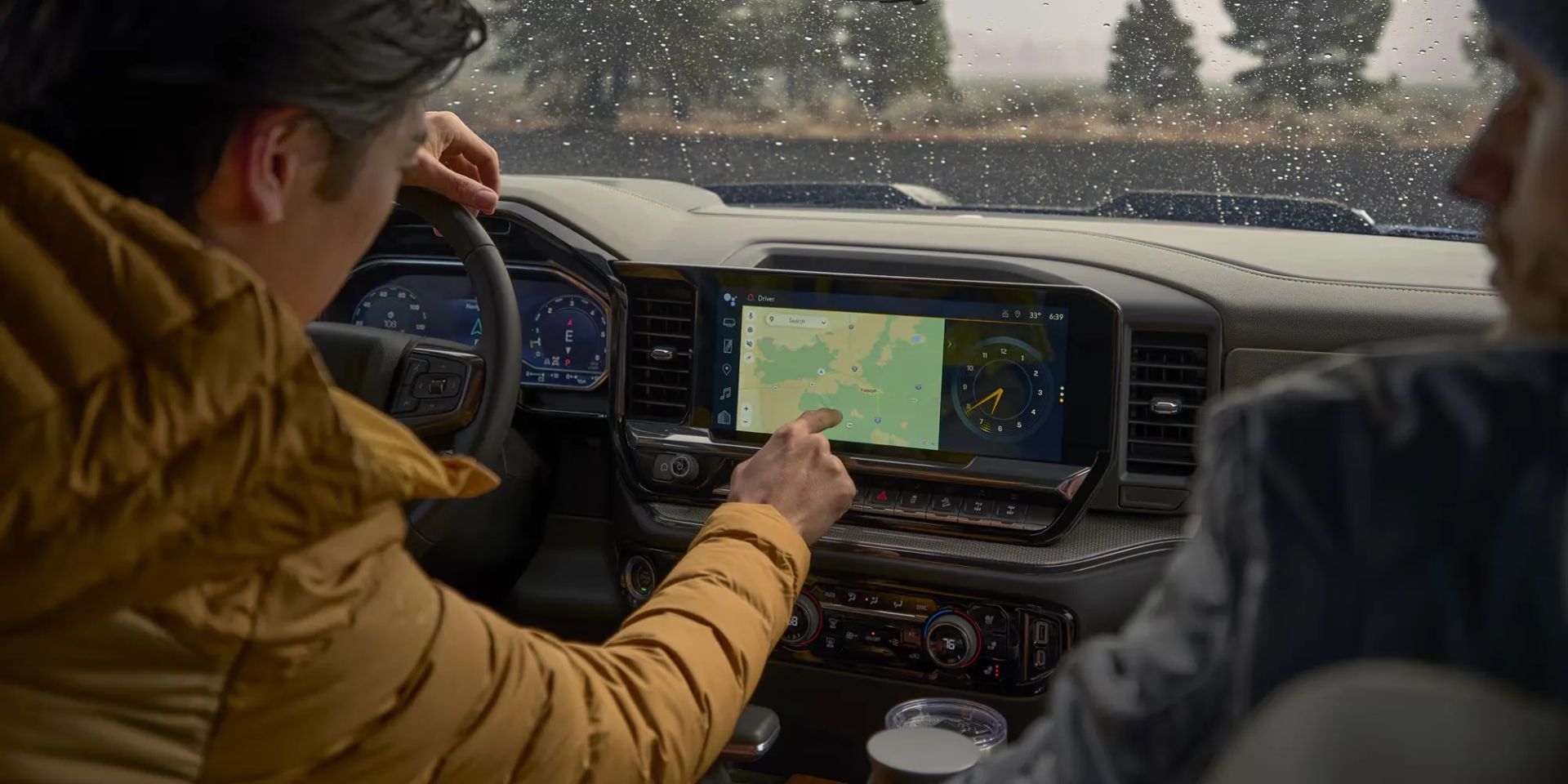 Vue intérieure du Chevrolet Silverado 1500 2026 avec conducteur utilisant l’écran tactile central pour la navigation, soulignant la connectivité avancée.