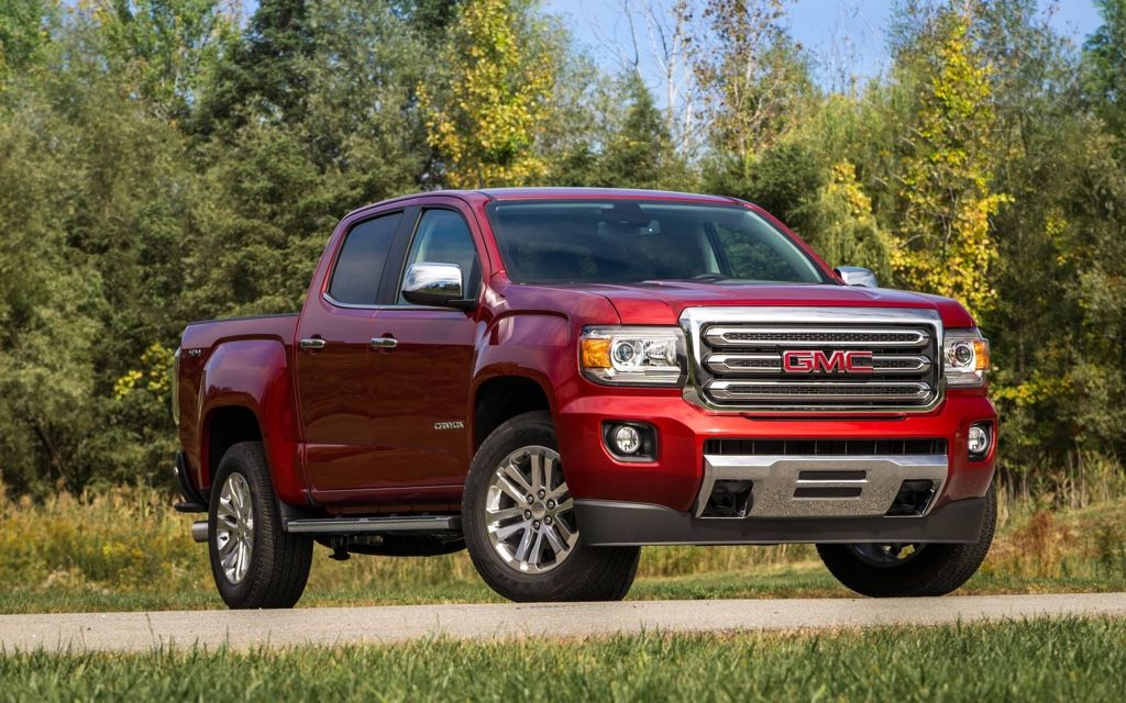 GMC Canyon rouge entre 2015 et 2022 garé sur une route de campagne, parfait exemple de camion usagé fiable.