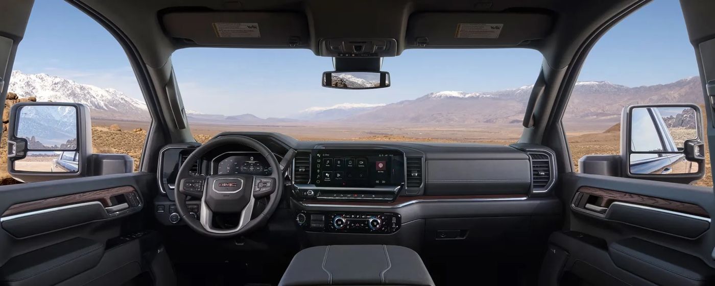 Intérieur raffiné du GMC Sierra HD 2026 avec vue panoramique sur les montagnes et tableau de bord moderne haut de gamme.