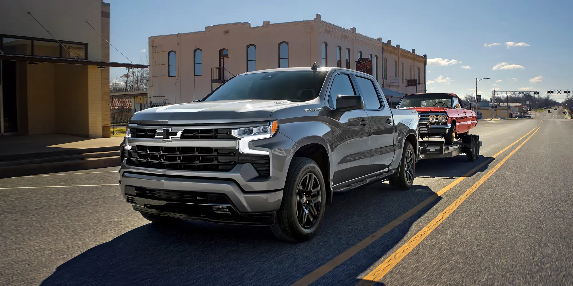 Chevrolet Silverado 1500 2026 gris remorquant une voiture classique rouge.