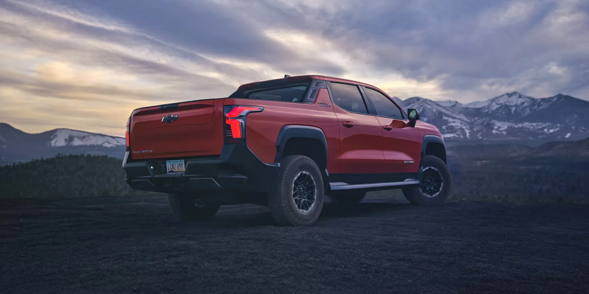 Chevrolet Silverado EV 2026 rouge vu de l’arrière devant des montagnes.