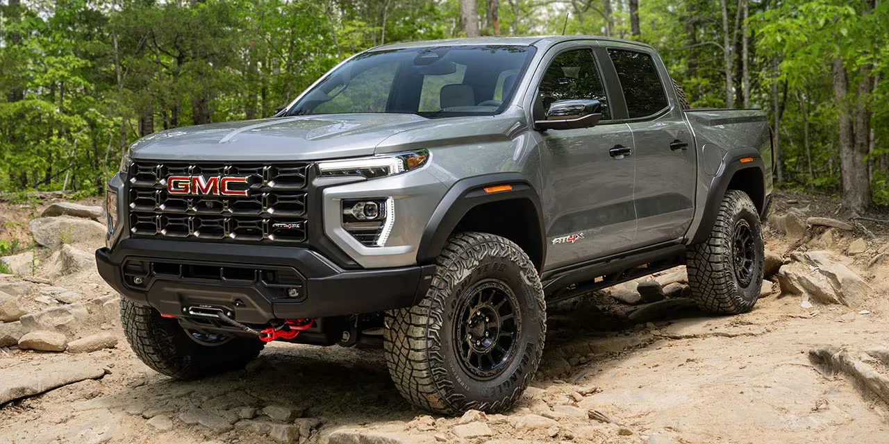 GMC Canyon 2026 gris sur un terrain rocheux en forêt.