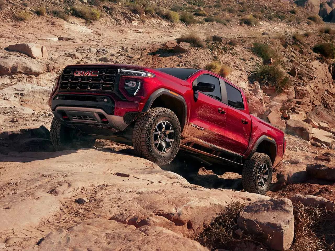 GMC Canyon 2026 rouge en conduite hors route sur des rochers.