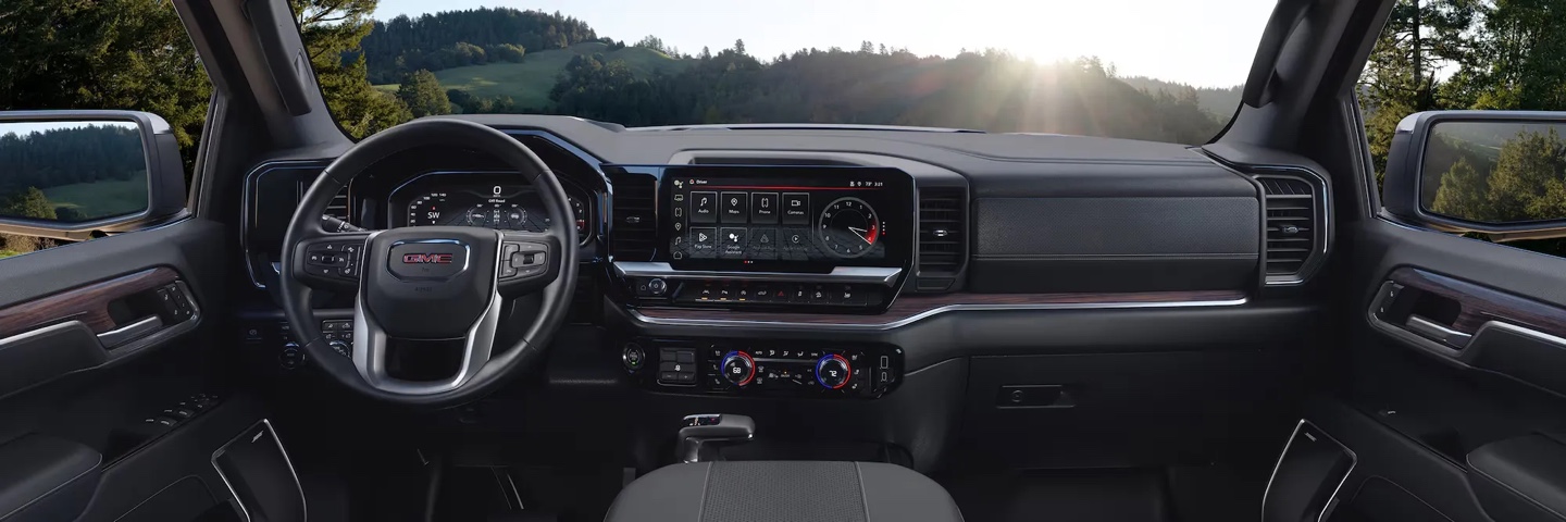 Intérieur du GMC Sierra 1500 2026 avec tableau de bord numérique et volant multifonction, mettant en valeur le confort et la technologie embarquée.